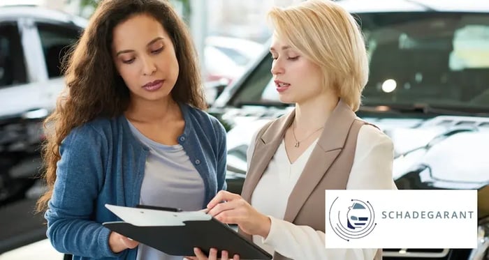 Twee dames kijken naar een auto contract met de Schadegarant logo in een hoekje-1