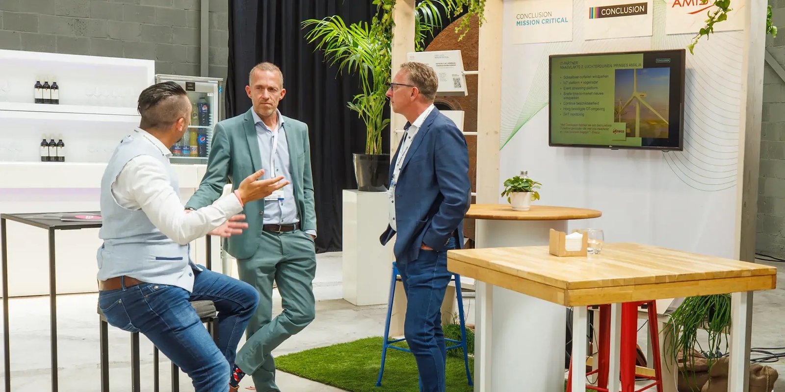 Drie mannen in zakelijke kleding die met elkaar praten in informele setting