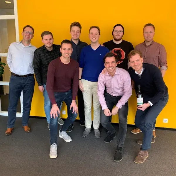 Groepje collega's van Integrations voor een gele muur