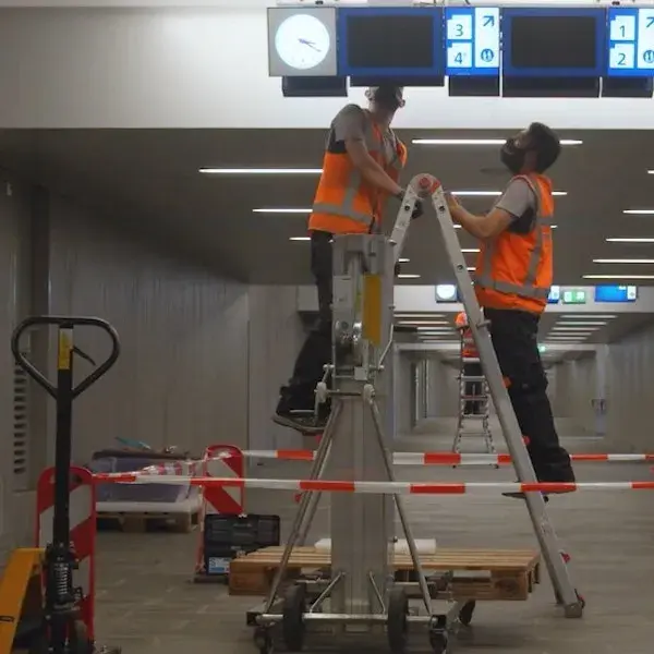 Twee collega's werken aan een informatie bord van NS