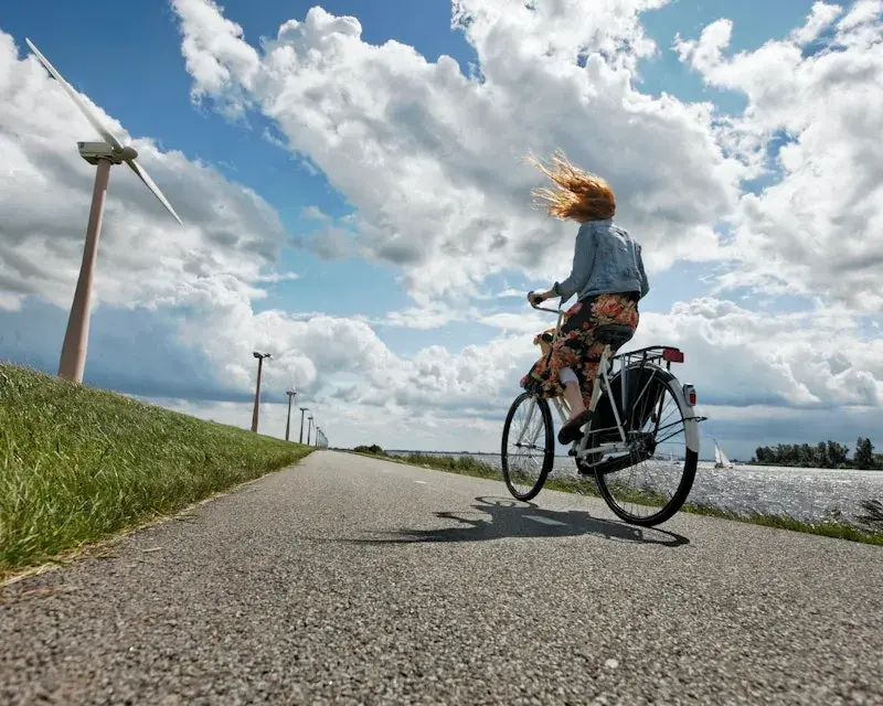 Fietsend meisje op een dijk langs windmolens