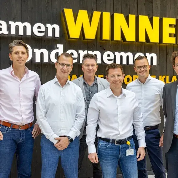 Groep mannen in wit overhemd lachen naar de camera