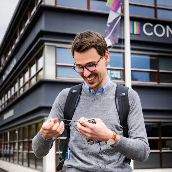 Man kijkt naar zijn telefoon en oortjes.