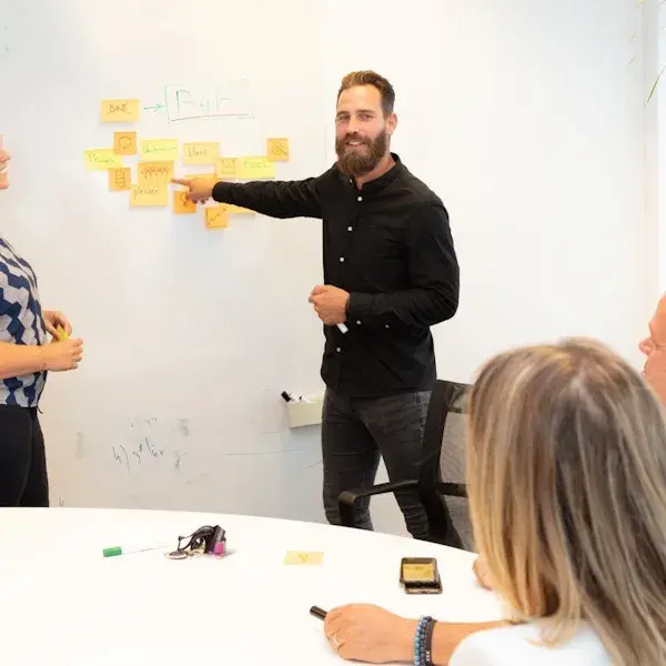 Collega wijst naar een whiteboard met post-its.