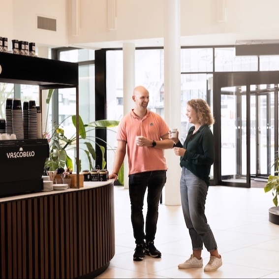 Colleagues are drinking coffee in the lobby of a building.