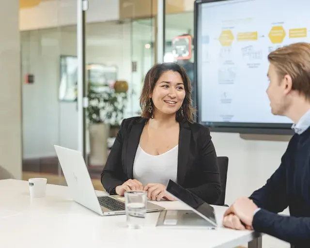 Vrouw kijkt lachend naar haar collega.