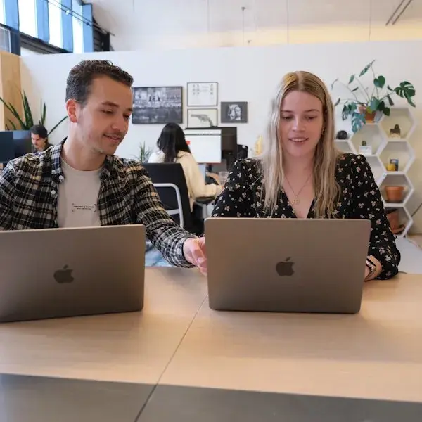 Twee collega's achter hun MacBook aan het werk