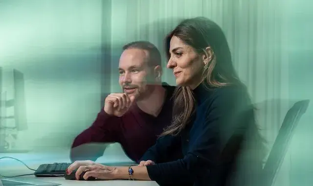 Lachende man en vrouw achter computer