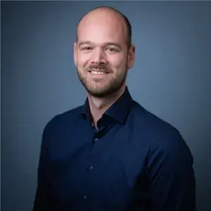 Man in donker overhemd lacht naar de camera