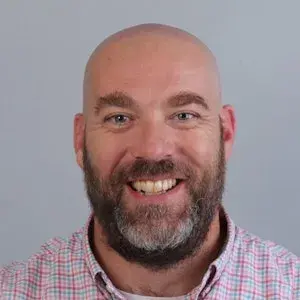 Lachende man met baard kijkt in de camera