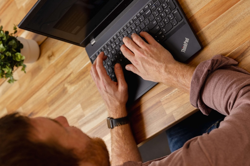 Man typt op zijn laptop.