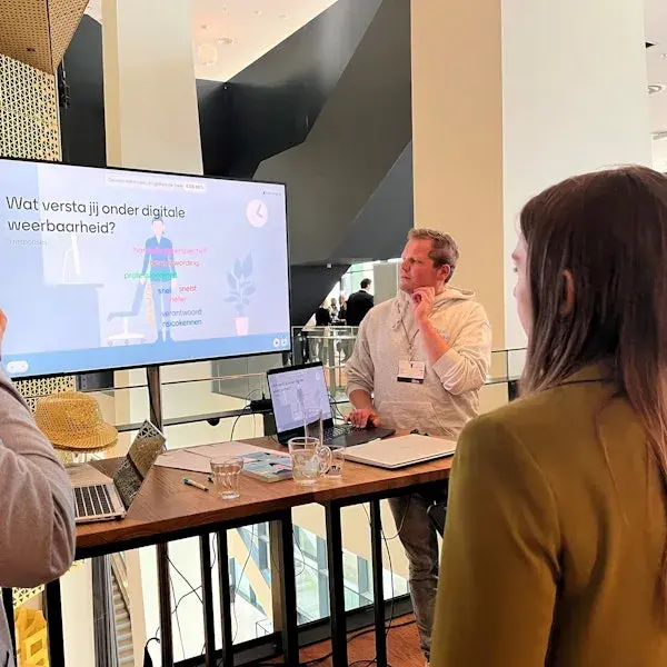 Niek laat op een groot scherm de module zien aan medewerkers bij de klant