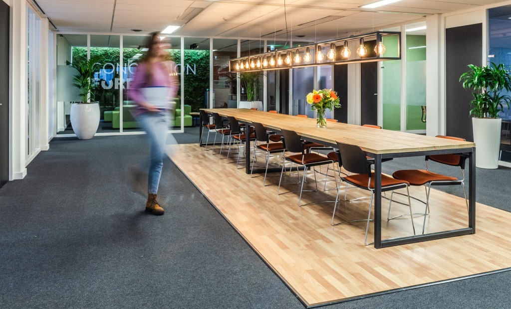 Vrouw loopt met laptop door kantoor