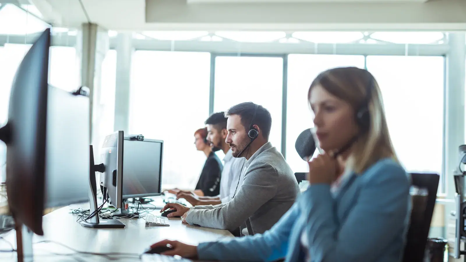 Collegas met een koptelefoon werken achten hun computers