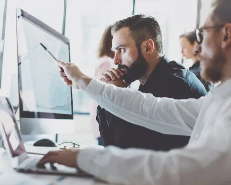 Collegas wijzen naar een scherm