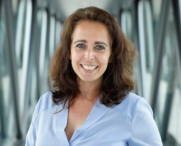 Vrouw met blauwe blouse kijkt in camera.