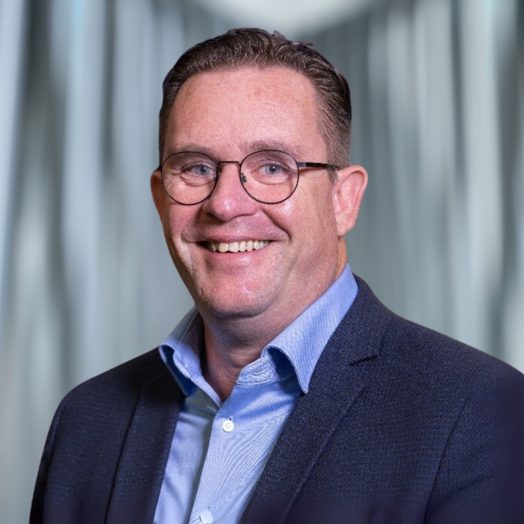 Mannelijke collega kijkt vriendelijk de camera in.